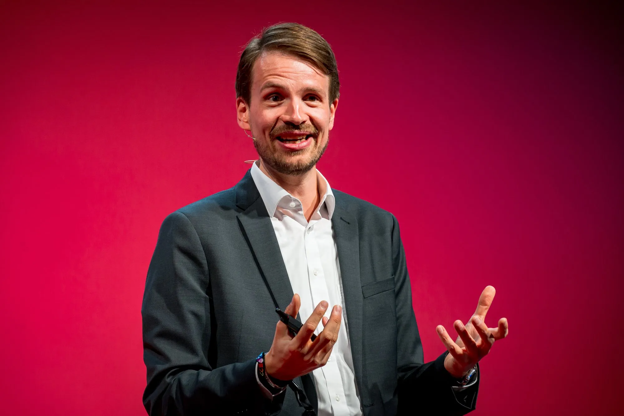 Prof. Dr. Jürgen Weimann während einer Keynote vor rotem Hintergrund